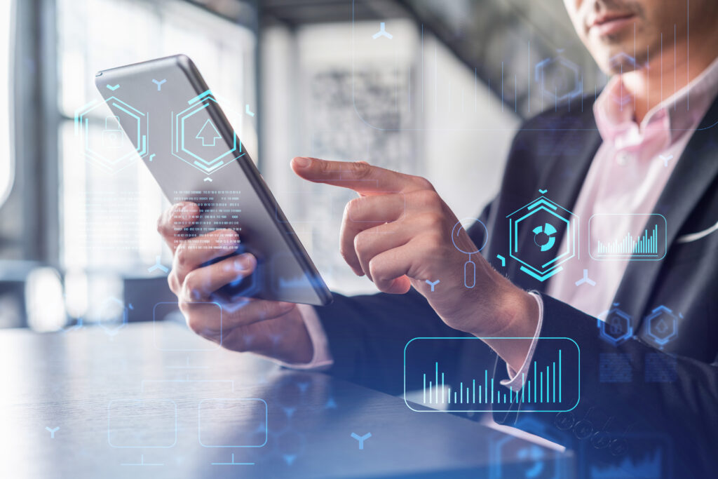 Profissional utilizando tablet com recursos digitais e gráficos, representando o uso de inteligência artificial na gestão e nos processos empresariais.